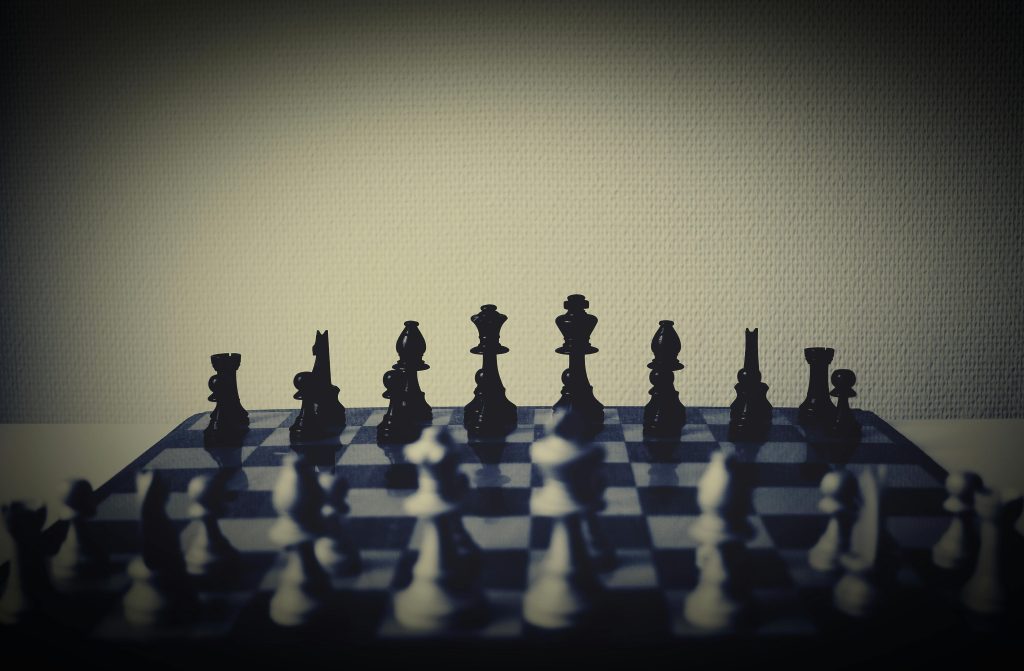 pexels-photo-112855-112855 A moody chessboard scene with shadows and prominent chess pieces in focus.