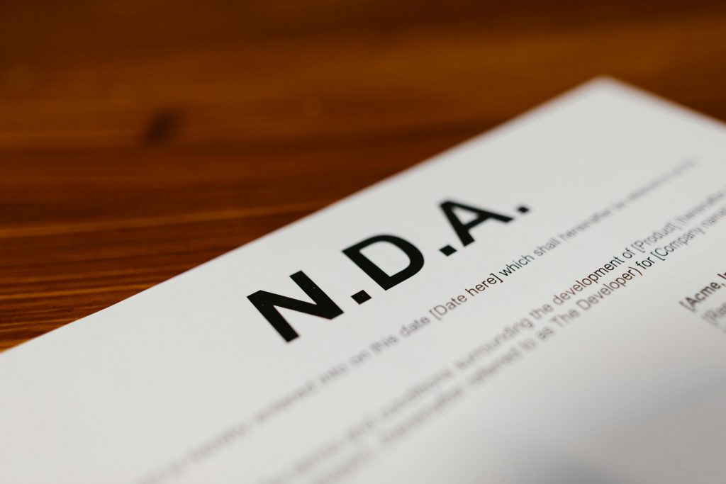 pexels-photo-7841406-7841406 Focused close-up of an NDA document on a wooden desk, highlighting contract details.